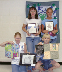 Blue Ribbon 4-H Club Members (l to r) Megan Powers and Rachel Powers (standing), Leah Wolfe and Anna Schutt (kneeling) displaying their Quilting and Arts and Craft projects.