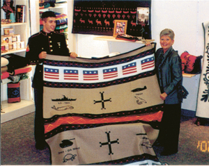 Top Prize “Code Talkers” Blanket will be raffled off at the Mihsihkinaahkwa Powwow in Columbia City.  Fort Wayne’s Pendleton Store in Covington Plaza donated this Indian Blanket. (L-R) Marine Lance Corporal Joe Tippmann (son of Powwow committee member Dani Tippmann) and Pendleton Store Manager Debbie Hallett present blanket.