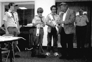 Scout John Dukarski watches as Scout Rob Dukarski and Scout Brian Shawver receive Press Corps awards from Editor Bob Stark. Miami District Commissioner Earl Kumfer observes the awarding. 