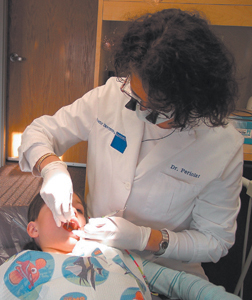 Dr. Catherine Periolet, in her office at 4626 W. Jefferson Blvd., exams Ashley’s teeth for proper hygiene.