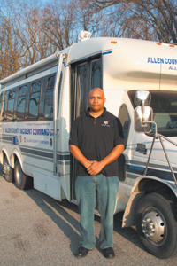 Detective Cornell Wiley stands in front of the Allen County Incident Command Unit. The unit gives officers a place at the crime scene where they can join together to compare notes and put together available information.