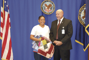 MSgt Cheryl Williams holds the Quilt of Valor quilt she chose for herself and her son, and Acting Associate Director Steve Clarke.