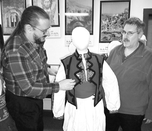 Marvin Moehle, right, gives guidance to Macedonian Museum volunteer Mark Miller on how to properly adjust the vest on the men’s festival clothing.
