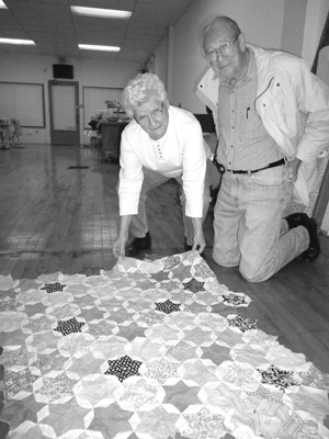 Ida and Morris Willett examine the scrap fabrics used by his mother Thelma to create a partial quilt top while awaiting his birth.