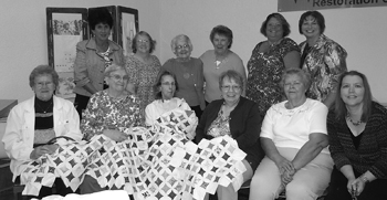 Members of the Lamplighters Homemakers Club and the cathedral window quilt started by the late Mary Wilhelm.