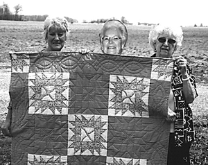 Sharon Ford (left) and Helen Gregory (right) admire the quilt made from family quilt blocks by Louise Bridges (center).