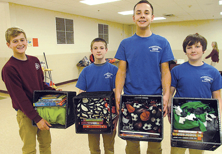 Four NJHS boys hold up milk crates recently packed with one blanket and six books.
