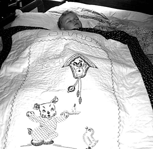 Connor sleeps beneath his “Good Night” quilt a gift from late Great-aunt Judi.