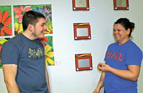 Curator Candy Pease (left) and artist Owen Sanders share a moment of laughter during the installation of “the Big Show” exhibit at Wunderkammer Company. On the wall are additional artworks created by Owen using the etch-a-sketch. Owen’s sister, Mackenzie, also has work featured in the exhibit. Both artists sold their creative works during the opening days of the month-long gallery exhibit.