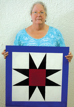 Artist and Waynedale native Julia Langmeyer prepares to hang a wooden star quilt block at Born Again Quilts.
