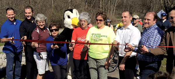 L-R: Warren Disch—Pizza Hut, Jordan Cornwell—Pres., Waynedale Business Chamber, Camille Garrison—Kingston Residence & Chair of Waynedale Trails and Sidewalks Initiative, Mary Stark—Curves, Penguin from Penguin Point, Beulah Matzak—Community Advocate, Dawn Ritchie—City of Fort Wayne Greenways and Trails Director, Alex Cornwell—The Waynedale News, Kent Castleman—Fort Wayne Trails, Inc. and Jason Arp—4th District City Councilman cut the ribbon commemorating a Waynedale Trail connection.