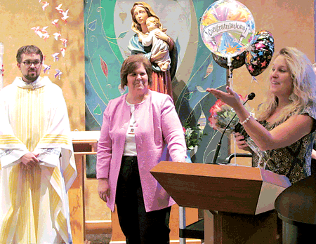 Mrs. Amy Bowman speaks to the congregation after the announcement that she is this year’s Saint Elizabeth Ann Seton Catholic School Light of Learning Award recipient. Father Matt Soberalski and Principal Lois Widner are pictured on the left.