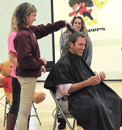Seventh grader Anna Topmiller shaves Mr. Greg Slee’s head. 